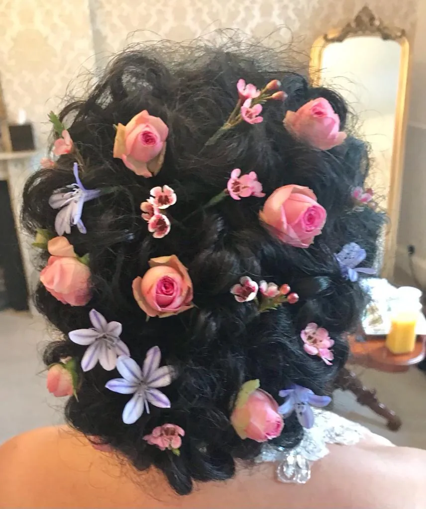 Dark curls studded with pink roses and blue star flowers